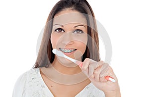 Attractive young woman with brackets cleaning her teeth