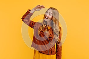Attractive young woman, in a bright yellow dress and an autumn jacket, posing on a yellow background. Autumn concept