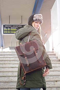 Attractive young woman with brown leather rucksack on stairs