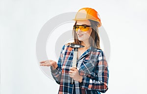 Attractive young woman in building helmet with hammer and orange protective glasses over the white background