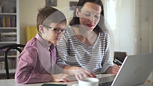 Attractive young woman and child are shopping online at table with laptop in apartment room spbd.