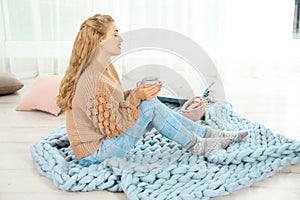 Attractive young woman in cozy warm sweater with cup