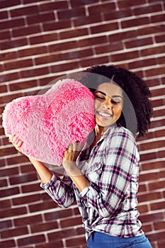 Attractive young woman cuddling with heart-shaped pillow