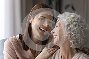 Attractive young woman cuddling smiling older retired mother