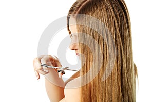 Attractive young woman is cutting her long natural hair.