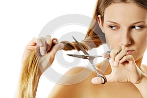 Attractive young woman is cutting her long natural hair