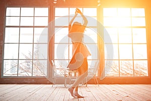 Attractive young woman dancing near huge wondows at her apartment