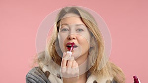 Attractive Young Woman Delicately Applying Pink Lipstick, Emphasizing Beauty in a Minimalist Pink