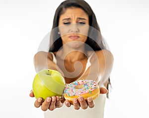 Attractive young woman on a diet deciding between an apple and a doughnut