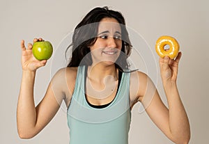 Attractive young woman on a diet deciding between an apple and a doughnut