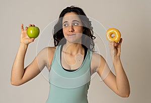 Attractive young woman on a diet deciding between an apple and a doughnut