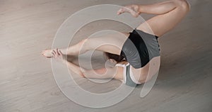 Attractive young woman does gymnastic exercises on the floor and stretches herself, yoga classes in slow motion, person