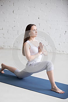 Attractive young woman doing anjaneyasana pose in white loft