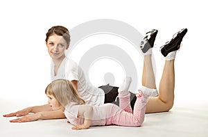 Attractive young woman doing sport exercises with her little daughter