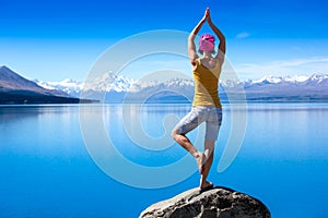 An attractive young woman doing a yoga pose for balance and stretching near the lake photo