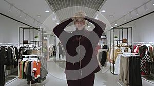 Attractive young woman dressed in a hoodie at clothing store, static shot