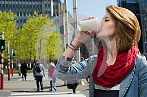 Attractive young woman drinking a hot drink from a paper cup