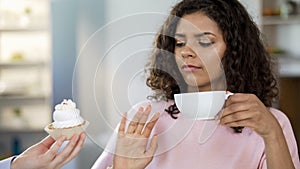 Attractive young woman drinking tea, saying no to cream-cake, healthy dieting
