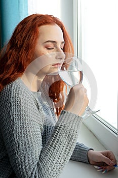 Attractive young woman drinking water at home