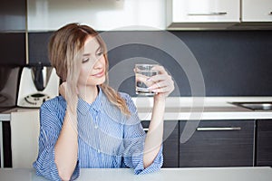Attractive young woman drinking water in the kitchen. Habits for a healthy lifestyle