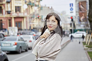 Attractive young woman in earphones listening to music outdoor. Audio healing, learning - taking webinar, casual