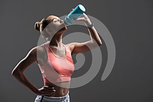 Attractive young woman enjoying drink after exercising