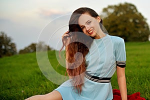 Attractive young woman enjoying her time outside in sunset park. Model girl with magnificent long hair posing outdoor. Beauty, fa