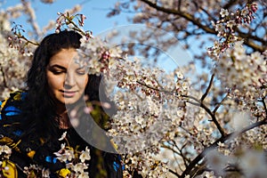 Attractive young woman enjoying spring among flowering trees in cherry orchard