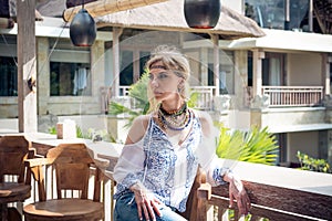 Attractive young woman in ethnic style look posing in tropical restaurant, portrait. Tropical island Bali, luxury resort