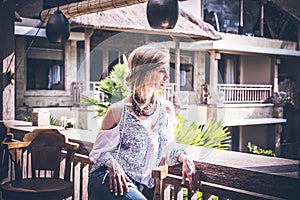 Attractive young woman in ethnic style look posing in tropical restaurant, portrait. Tropical island Bali, luxury resort