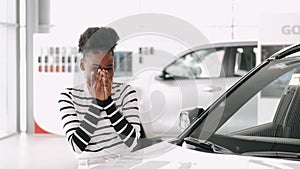 Attractive young woman is getting new car at car dealership
