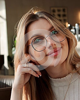 Attractive young woman in glasses, sitting in a cafe, looks seductively away