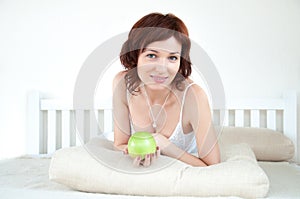 Attractive young woman with an green apple at bed