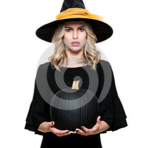 Attractive young woman in Halloween Witch costume holding large black pumpkin, looking confused. Halloween concept.