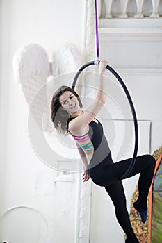 Attractive young woman hanging on the aerial hoop upside down