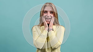Attractive young woman having stunned and shocked look on a turquoise background.