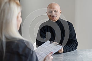 Attractive young woman helping senior man with questionnaire, pensioneer filling papers at nursing home, having