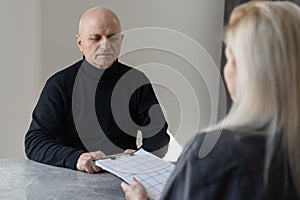 Attractive young woman helping senior man with questionnaire, pensioneer filling papers at nursing home, having