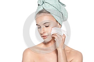 Attractive young woman with her hair wrapped in a towel, removing make up. Pretty girl with perfect complexion cleansing her face. photo