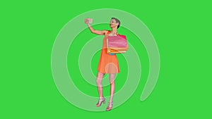 Attractive young woman holding different blank shopping bags making selfie on a Green Screen, Chroma Key.