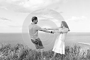 attractive young woman holding hands of man dancing in the meadow.