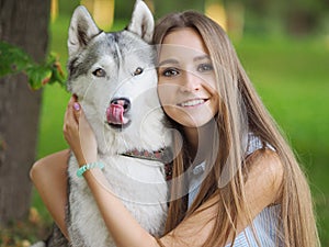 Attractive young woman hugs funny siberian husky dog with brown eyes