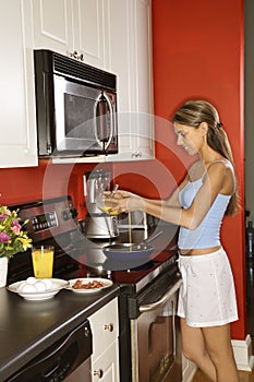 Attractive Young Woman in Kitchen Cooking Breakfas