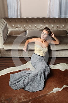 Attractive young woman in long fashionable dress resting at home