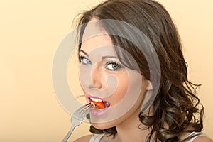 Attractive Young Woman Looking at the Camera Eating a Tomato