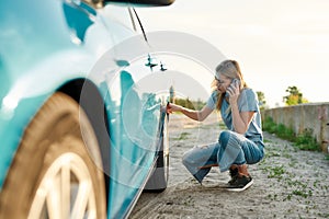 Attractive young woman looking sad, calling car service, assistance or tow truck while having troubles with her auto