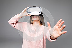 Attractive young woman looking through virtual reality headset, indoor shot over white background. caucasian looking female model