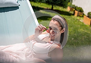 Attractive young woman lying in hammock smiling looking at camera