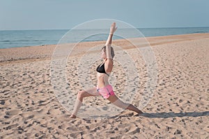 Attractive young woman making yoga on the beach