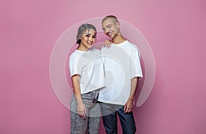 Attractive young woman and man wearing white empty t-shirt on bright pink studio wall banner background